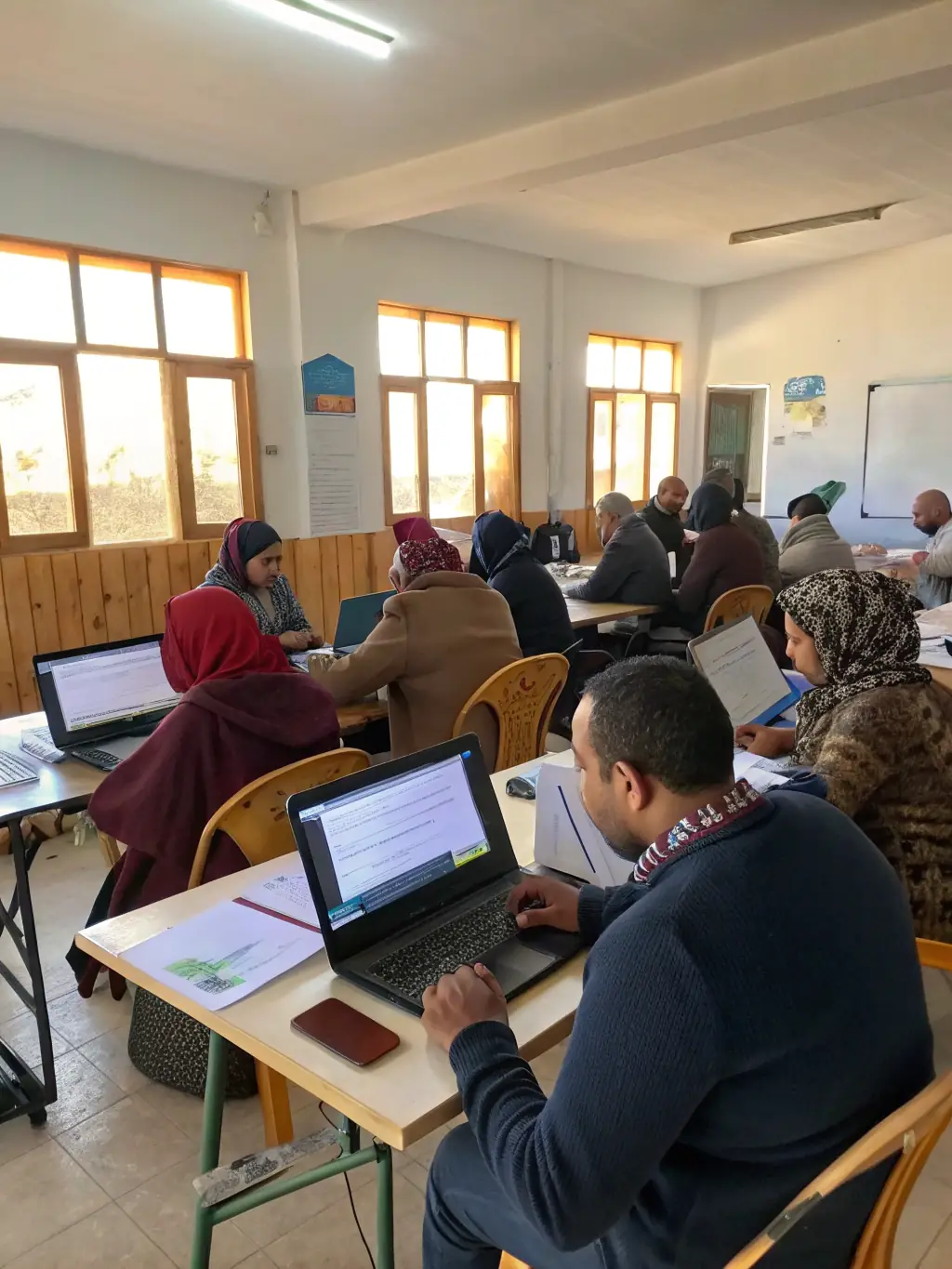A diverse group of adults attending a digital literacy workshop, learning how to use computers and access online resources. The atmosphere is supportive and encouraging.